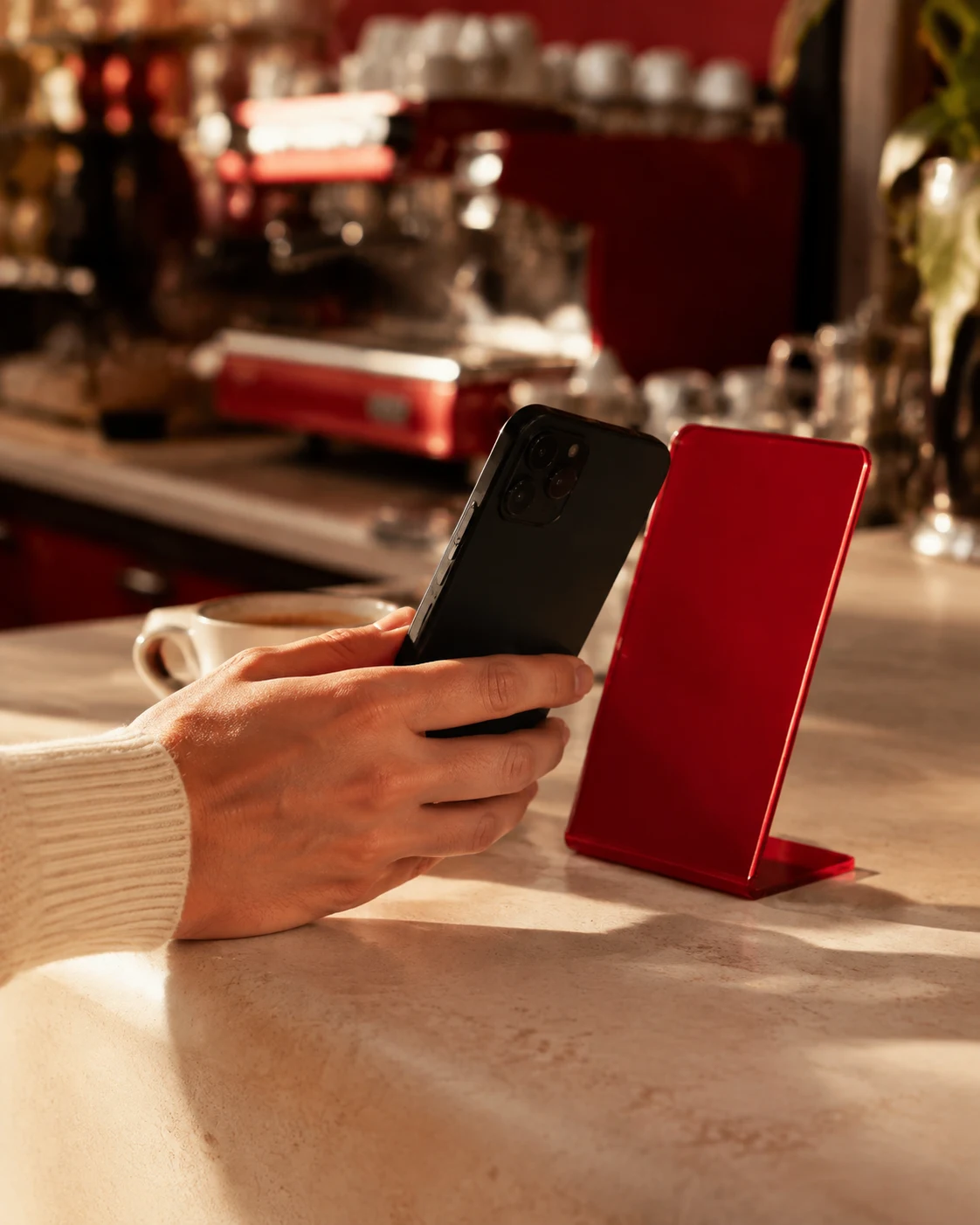 Pessoa aproximando um celular de uma placa vermelha no balcão de uma cafeteria